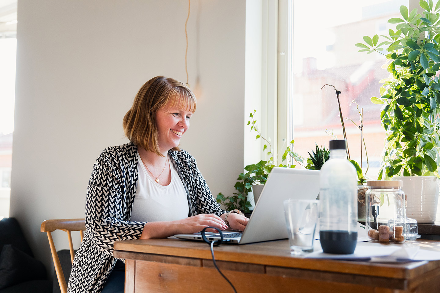 Linnea Holm sitter vid köksbord och arbetar vid datorn