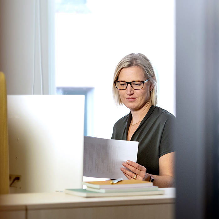 Kvinna kollar på papper vid skrivbord