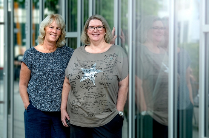 Susanne och Maria står lutade mot en glasvägg