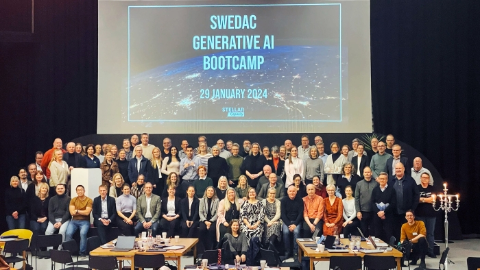 Swedacs alla medarbetare samlade på scenen framför en skärm där det står 