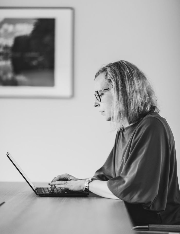 Elisabeth Hallin-Bergvall arbetar på sin laptop sett från sidan. 