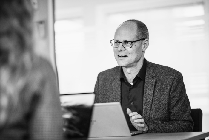 Fredrik sitter och pratar med en person framför sig som man inte ser i bild.