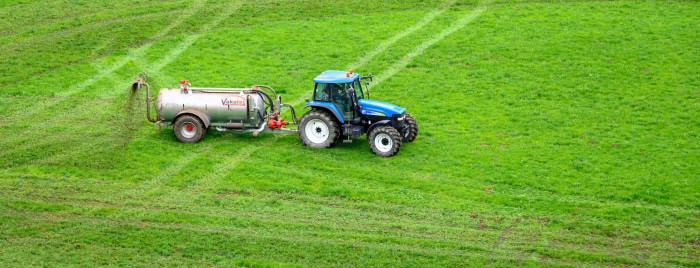 Traktor med tank som sprider ut gödsel på en åker.