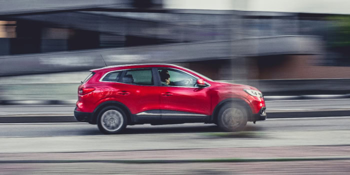 En röd bil i snabb rörelse på en väg.