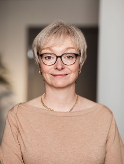 porträtt av Kristina Hallman som kollar rakt in i kameran och ler.